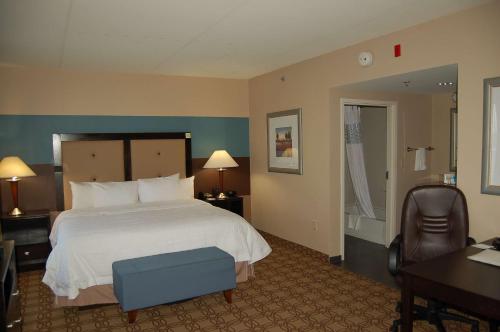 a hotel room with a large bed and a chair at Hampton Inn & Suites Charlotte-Airport in Charlotte