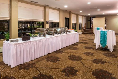 a row of tables with white table cloths in a room at Hilton Garden Inn Detroit Southfield in Southfield