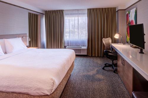 a hotel room with a bed and a flat screen tv at Hilton Garden Inn Detroit Southfield in Southfield