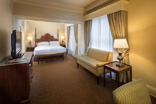 a hotel room with a bed and a chair at The Seelbach Hilton Louisville in Louisville