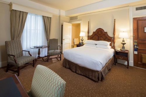 a hotel room with a bed and a table and chairs at The Seelbach Hilton Louisville in Louisville