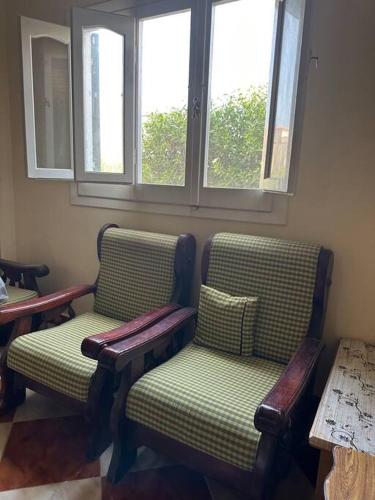 a room with two chairs and a table and windows at North coast rent Chalet / شاليه للايجار في الساحل in Dawwār Abū Duray‘ah ‘Abd al Karīm