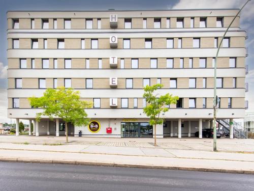 um edifício alto e branco com árvores em frente em B&B Hotel Landshut em Landshut