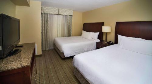 a hotel room with two beds and a flat screen tv at Hilton Garden Inn Valdosta in Valdosta