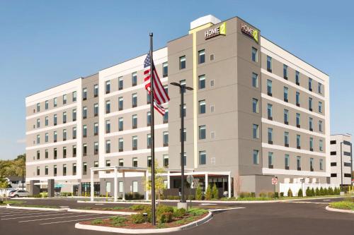 an office building with an american flag in front of it at Home2 Suites By Hilton Hasbrouck Heights in Hasbrouck Heights