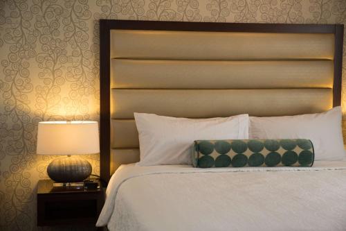 a bedroom with a bed with a headboard and a lamp at Hilton Garden Inn Montebello / Los Angeles in Montebello