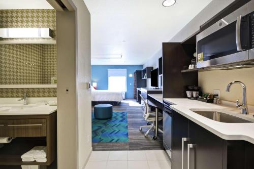 a kitchen with a sink and a room with a bed at Home2 Suites By Hilton Carbondale in Carbondale