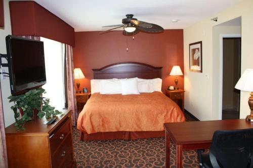 a hotel room with a bed and a flat screen tv at Homewood Suites Saint Cloud in Saint Cloud