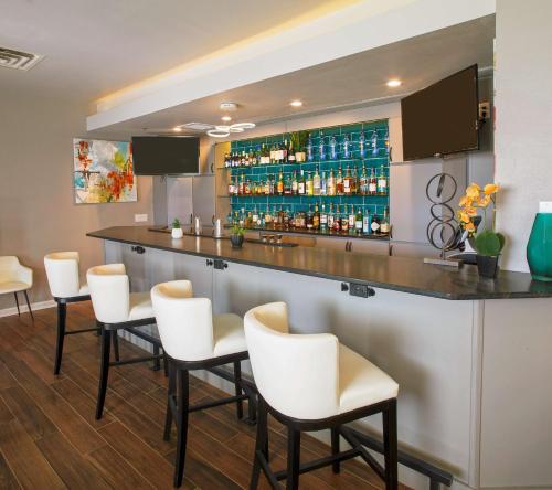 a bar with white chairs and a counter with alcohol bottles at Hilton Garden Inn Bentonville Rogers in Bentonville