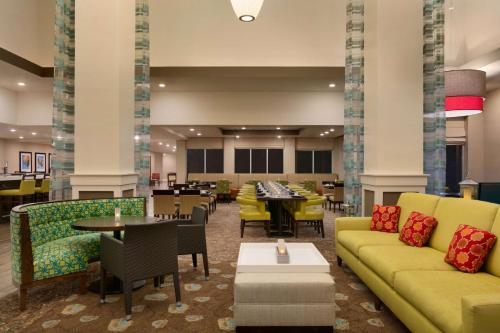 a lobby with yellow couches and tables and chairs at Hilton Garden Inn Statesville in Statesville