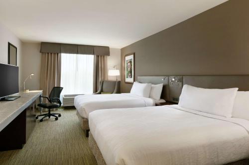 a hotel room with two beds and a desk at Hilton Garden Inn Statesville in Statesville