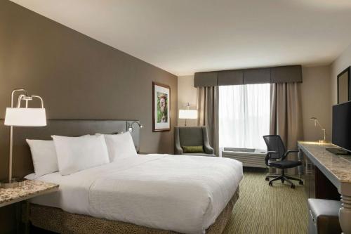 um quarto de hotel com uma grande cama branca e uma secretária em Hilton Garden Inn Statesville em Statesville
