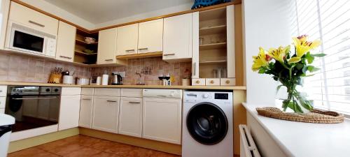 a kitchen with a washing machine and a vase of flowers at 9 The Downs, Thurlestone, South Devon on the coastal footpath overlooking Burgh Island in Thurlestone