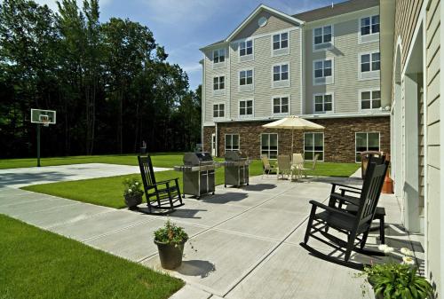 a patio in front of a building with chairs and an umbrella at Homewood Suites by Hilton Portland in Scarborough