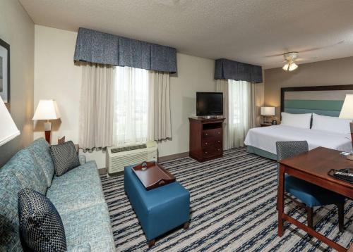 a hotel room with a bed and a couch and a desk at Homewood Suites by Hilton Portland in Scarborough