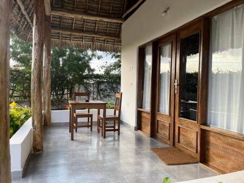 a patio with a table and chairs and a door at MITI Beach Bungalows in Nungwi