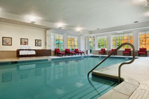 a swimming pool in a building with red chairs at Hilton Pearl River in Pearl River