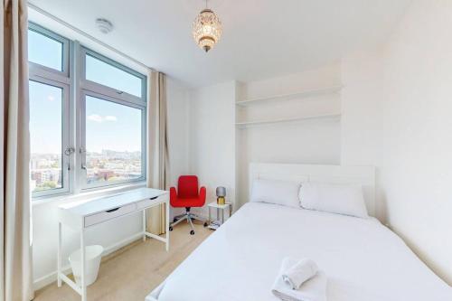 a white bedroom with a white bed and a red chair at Spacious 3 bed with city views in Limehouse in London