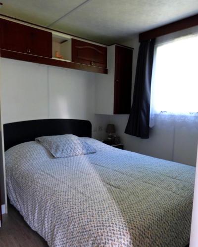 une chambre avec un grand lit avec une fenêtre dans l'établissement Mobile Home Auvergne, à Besse-et-Saint-Anastaise