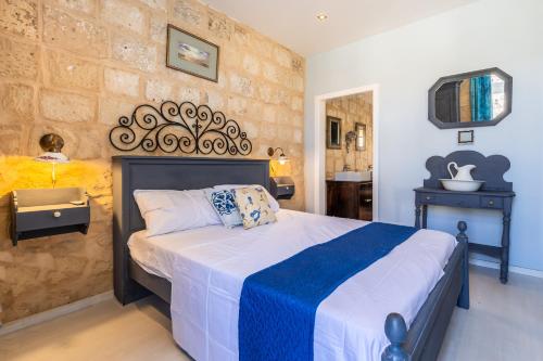 a bedroom with a bed with a blue and white blanket at Valletta Bastions Seafront House in Valletta