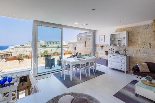 a living room with a table and a large window at Valletta Bastions Seafront House in Valletta