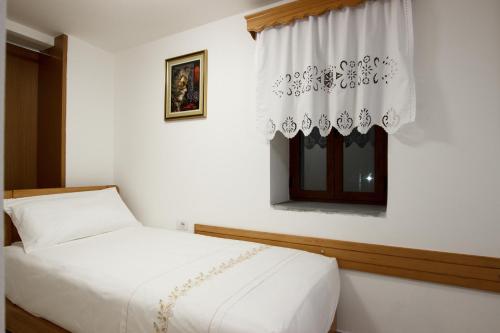 ein weißes Schlafzimmer mit einem Bett und einem Fenster in der Unterkunft GUEST HOUSE ÇANI in Gjirokastër