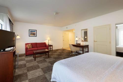 a hotel room with a bed and a red couch at Hampton Inn & Suites Baton Rouge - I-10 East in Baton Rouge