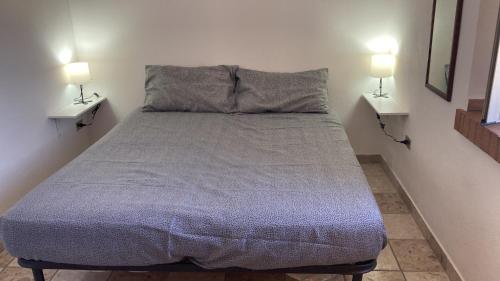 un letto in una camera con due lampade a muro di Casa Gialla - Bilocale indipendente a Soverato Superiore