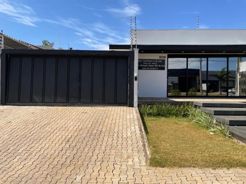 a garage with a black gate in front of a building at Unidades mobiliadas em condomínio in Lucas do Rio Verde