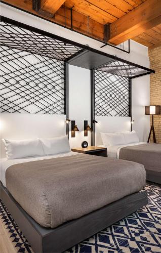 a bedroom with two beds and a table with lamps at Canopy by Hilton Minneapolis Mill District in Minneapolis