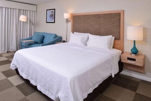a bedroom with a large bed and a blue chair at Hampton Inn Tulsa Sand Springs in Tulsa