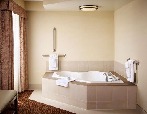 a bathroom with a tub and towels on the wall at Hampton Inn by Hilton North Bay in North Bay