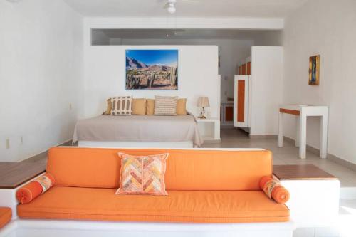un divano arancione in una camera con letto di Casa Faro a Troncones