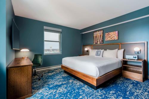 a hotel room with a bed and a desk and a television at Hotel Elkhart, Tapestry Collection By Hilton in Elkhart
