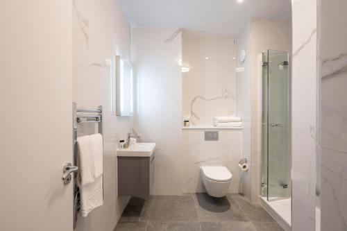 Un baño blanco con inodoro y lavabo. en Tower Residences by Blue Orchid, en Londres