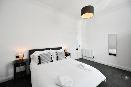 a white bedroom with a white bed and two lamps at Prestwick Pink Pad in Prestwick