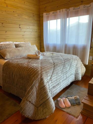 a bedroom with a bed with a window and shoes at Chalé Vale das Pedras in Praia Grande