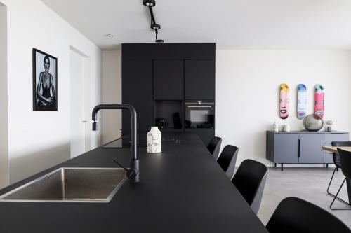 a kitchen with a black counter top and a sink at Design Apartment with 60m² terrace - heated inside pool and wellness facilities - very close to the beach in Cadzand