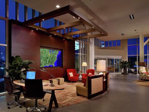 a lobby with red chairs and tables in a building at DoubleTree Hotel & Suites Charleston Airport in Charleston