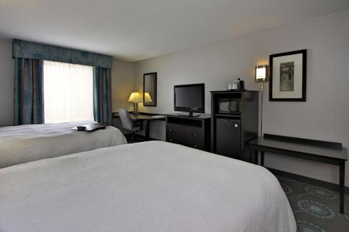 a hotel room with two beds and a television at Hampton Inn Defiance in Defiance
