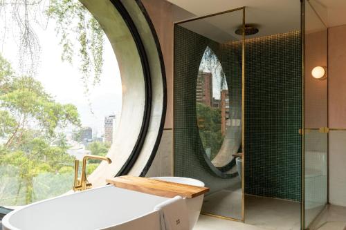 a bathroom with a tub and a large window at 23 Hotel Medellin in Medellín