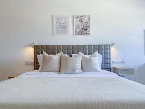 um quarto com uma cama grande com lençóis brancos e almofadas em Phaedrus Living: Plateia Suite Brillante em Nicósia