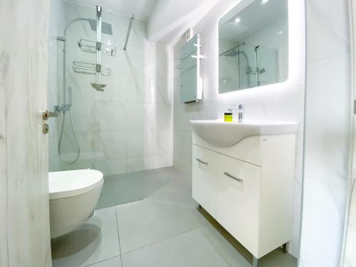 uma casa de banho branca com um lavatório e um WC em Phaedrus Living: Plateia Suite Brillante em Nicósia