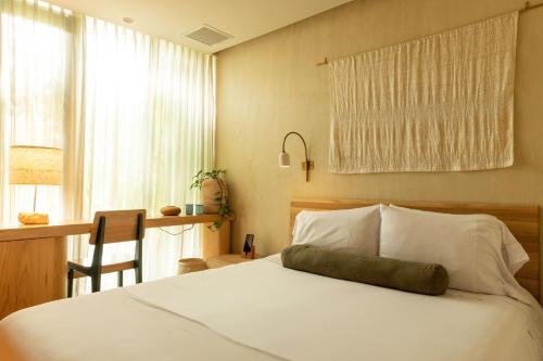 a bedroom with a bed and a desk and a window at 23 Hotel Medellin in Medellín