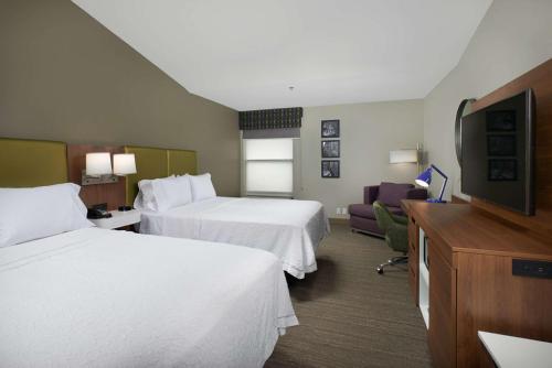 a hotel room with two beds and a flat screen tv at Hampton Inn Butte in Butte
