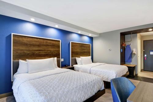two beds in a room with a blue wall at Tru By Hilton Richmond in Richmond