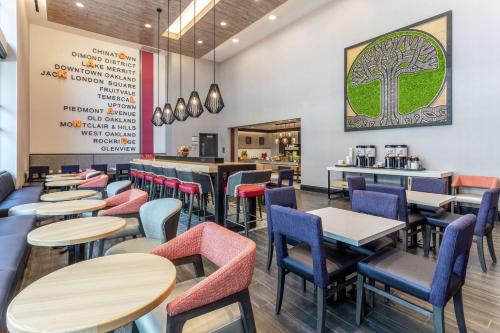 ein Restaurant mit Tischen und Stühlen und einem Baum an der Wand in der Unterkunft Hampton Inn Oakland Downtown-City Center in Oakland