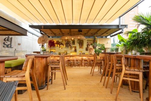 a restaurant with a bar with wooden tables and chairs at 23 Hotel Medellin in Medellín