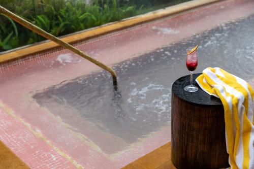 - un bain à remous avec un verre de vin sur une table dans l'établissement 23 Hotel Medellin, à Medellín