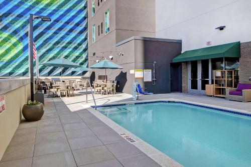 a swimming pool with tables and chairs and a building at Home2 Suites By Hilton Charlotte Uptown in Charlotte